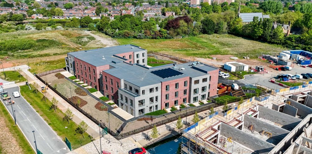 Aerial image showing the red and grey brick fronted Trafford Waters Care Home building with a glimpse of other ongoing construction in the area