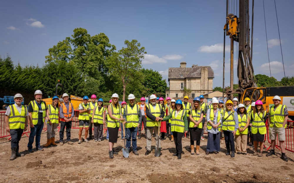 People in hi vis in front of construction machinery celebrating the start of site of Majority LGBTQ+ housing development